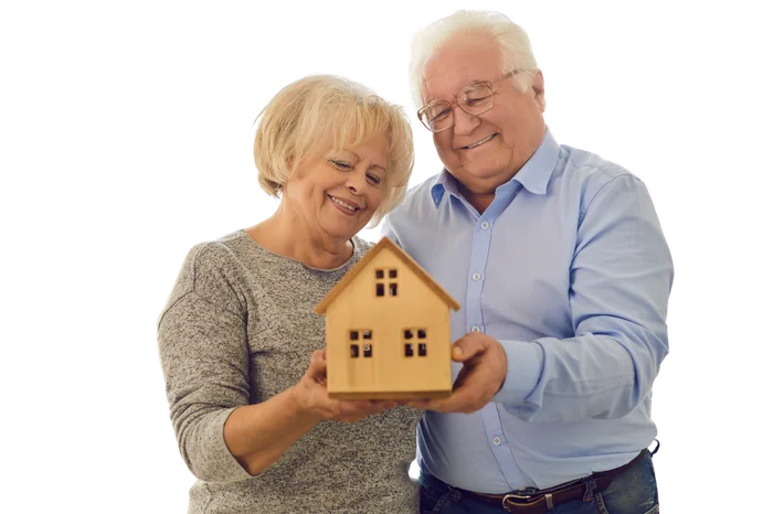 Pareja de adultos mayores sosteniendo una casa de madera, representando el Seguro de Vida